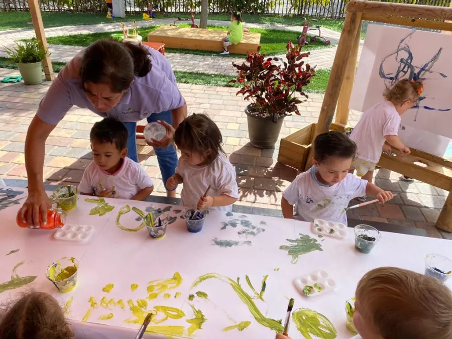 Toddlers painting outside and teacher
